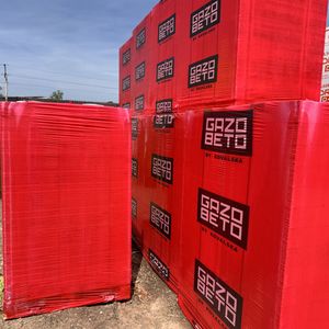 Піддони газоблоку GAZOBETO від Ковальської у червоній плівці, складені у два яруси на майданчику